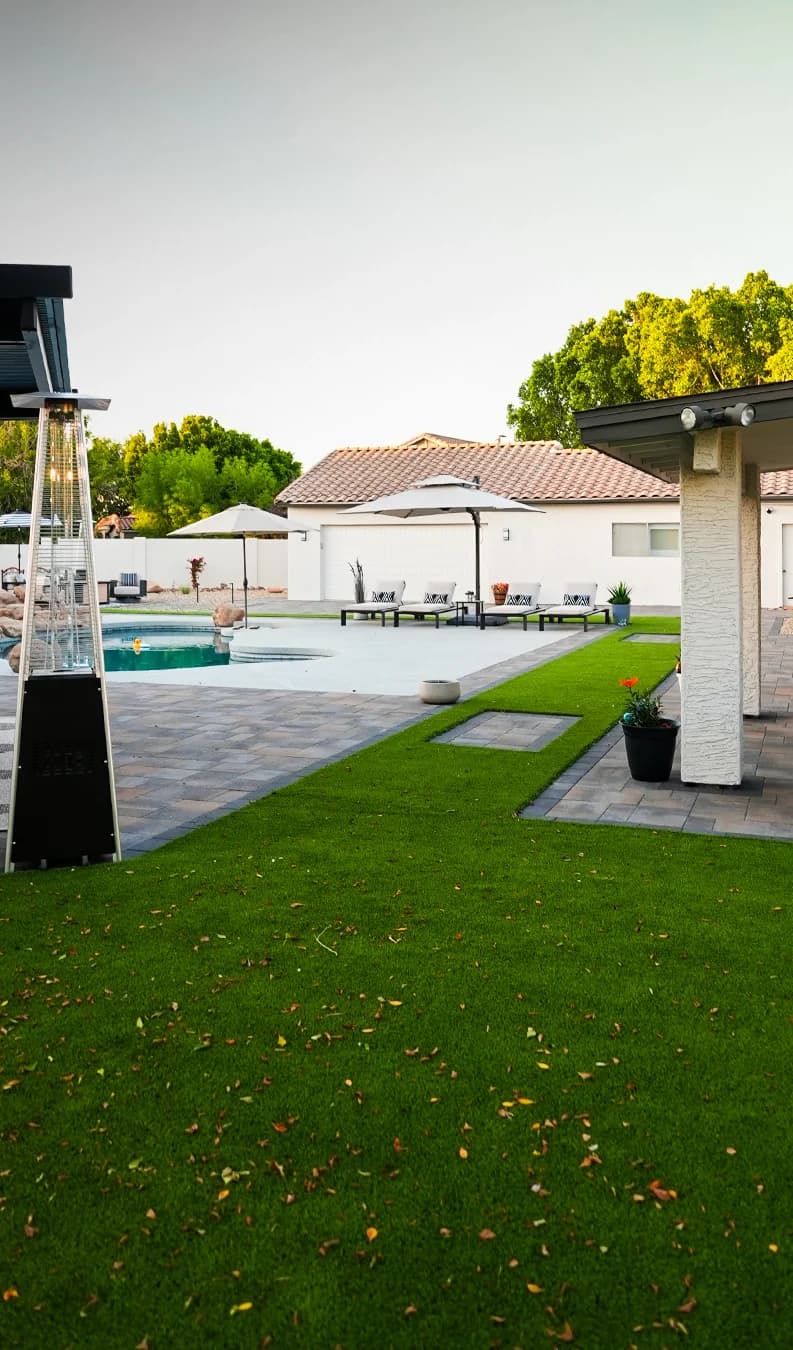 A TurfIt backyard lawn beside a paver patio and pool, a patio heater and umbrellas